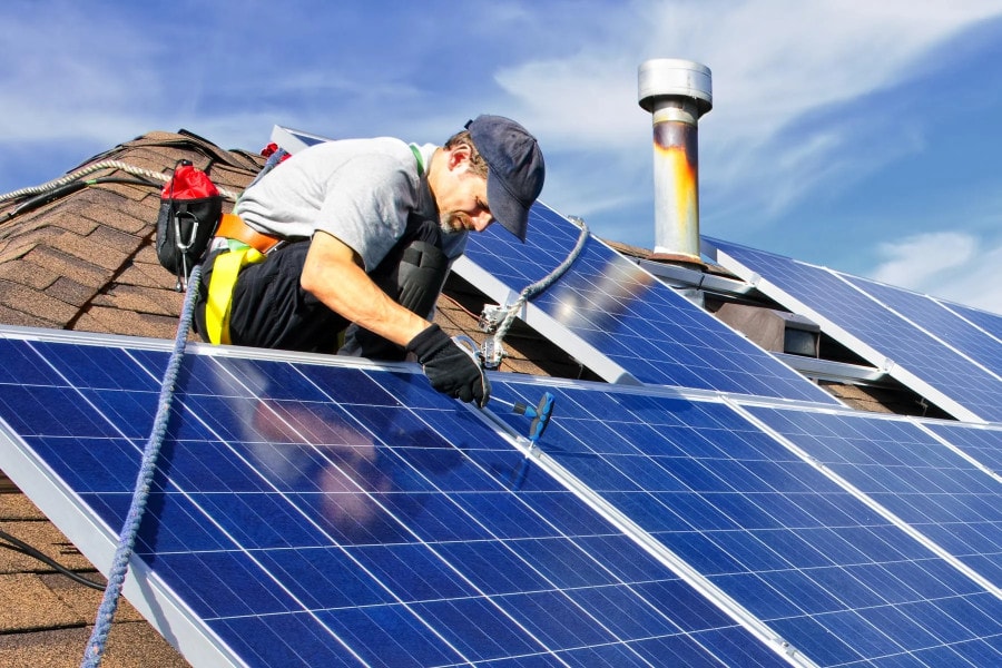 Técnico instalando paneles solares en techo residencial